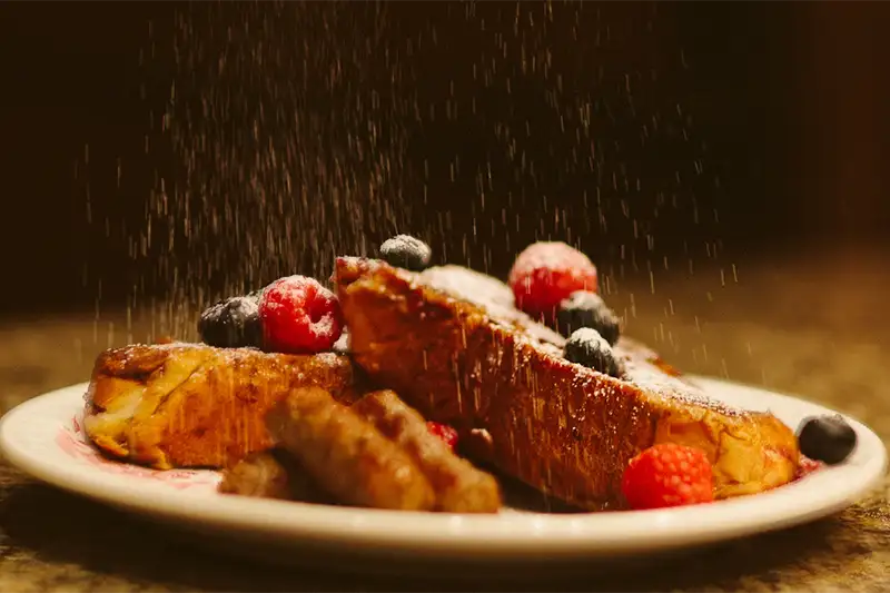 Thick-cut brioche French toast topped with fresh raspberries, blueberries, and powdered sugar at The Buckingham Inn bed and breakfast in Madison, WI.