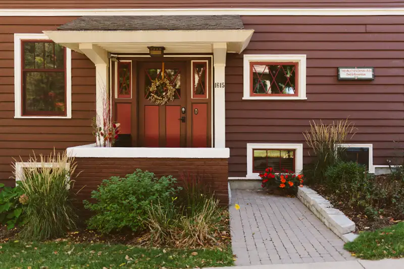 Front entrance to The Buckingham Inn, with historic red and brown door, and exterior flowers and perennials.