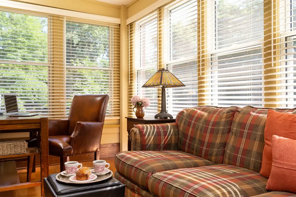 Bright sunroom in a Madison WI bed and breakfast common area with a mission-style desk, comfortable seating, and morning coffee for a relaxing getaway.
