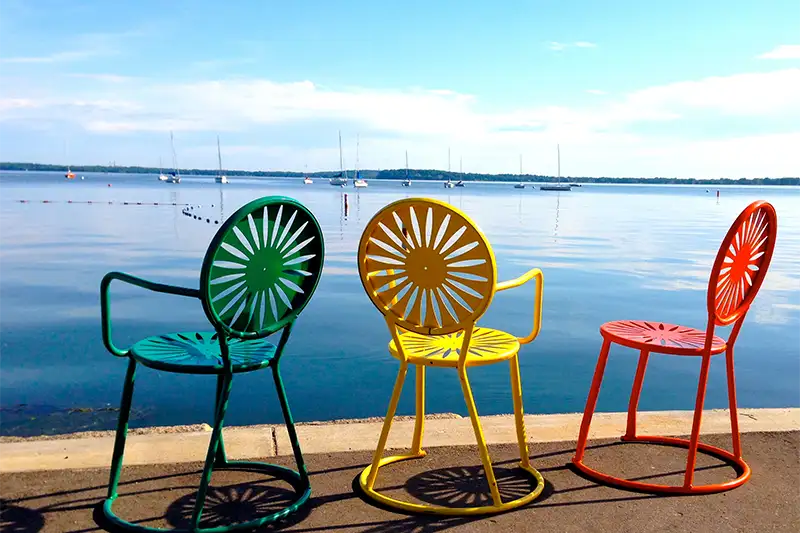 Colorful green, yellow, and orange chairs by the water in Madison, WI—stay at The Buckingham Inn for easy access to Memorial Union.