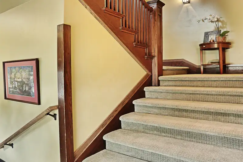 Elegant wooden staircase with patterned carpeting and vintage decor at The Buckingham Inn, a historic bed and breakfast in Madison, WI