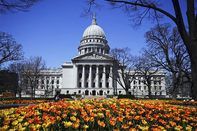 The Wisconsin State Capitol building in Madison viewed behind a vibrant field of orange and yellow tulips, a must-see landmark near The Buckingham Inn.